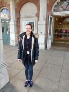 Young woman standing outside museum entrance wearing a coat